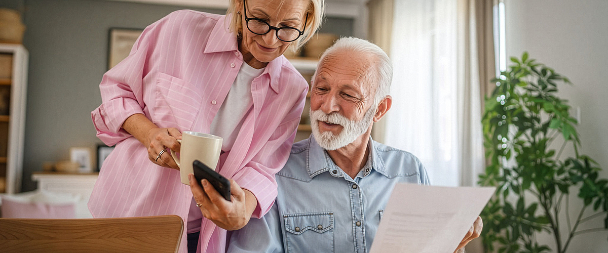 Ein älteres Paar sitzt im Wohnzimmer und recherchiert zu Förderungen